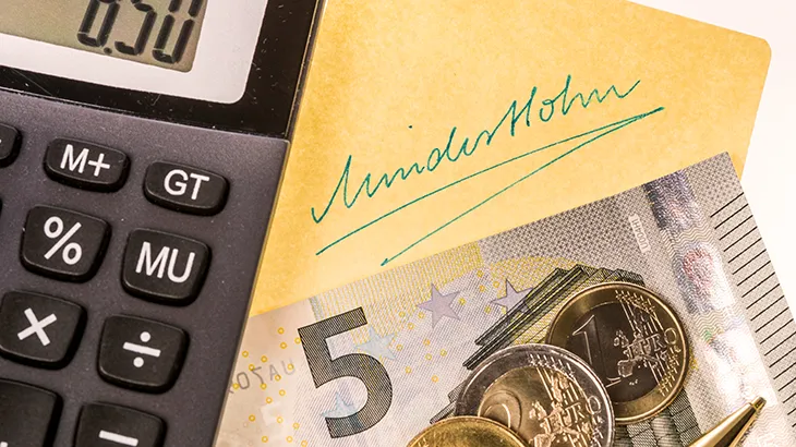 Mindestlohn ist Grundlage für Nachtzuschläge und Feiertage; Taschenrechner, Geld und ein Postit mit Mindestlohn in Handschrift notiert